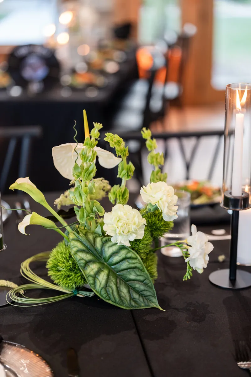 Close-up of tropical table floral arrangement with anthurium calla lilies and greenery