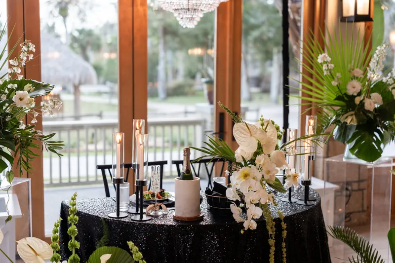 Sweetheart table with black sequin tablecloth champagne orchids and chandelier overhead
