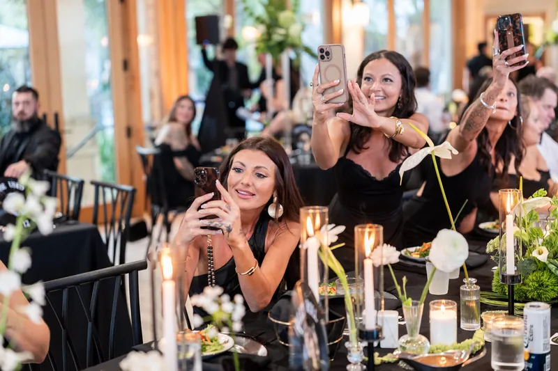 Guests holding up phones and filming during reception toasts