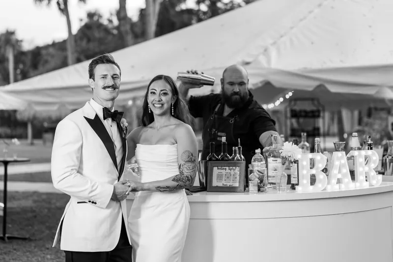 Couple posing at the bar while bartender shakes cocktails in black and white