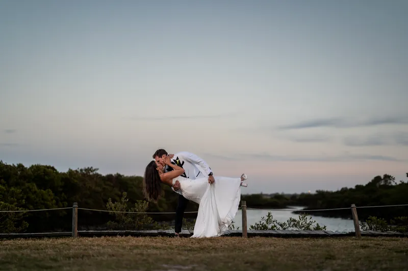 Dramatic dip kiss at sunset with water and marshland in background