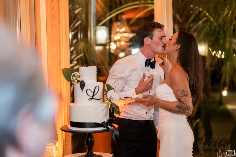 Couple kissing next to their wedding cake during cake cutting at reception