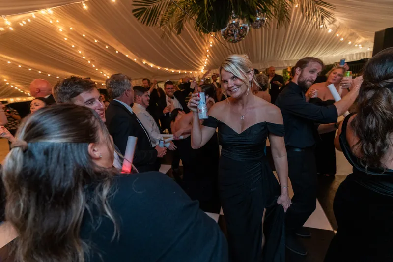 Guests dancing under the tent with disco ball and string lights