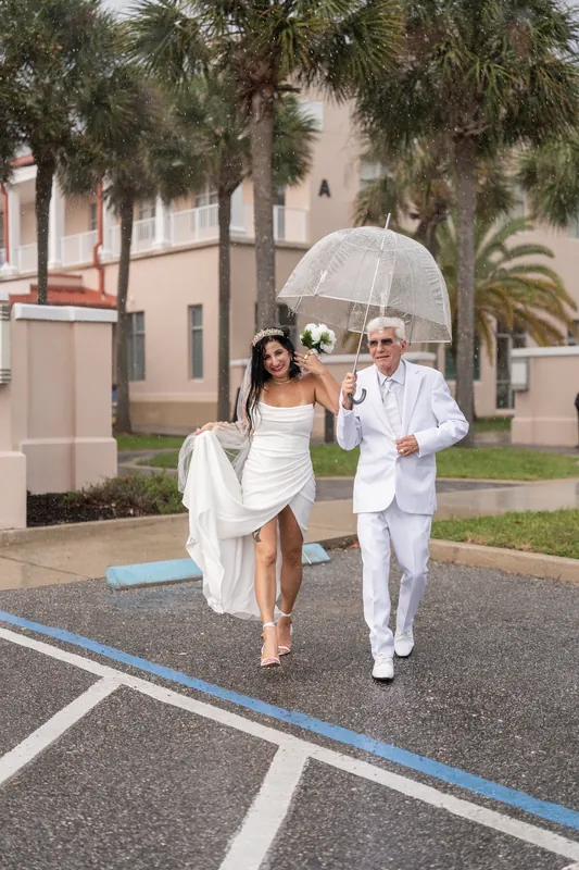 Isury and Mike jog across the courthouse driveway in the rain, white clothing and umbrella creating a dynamic moment.