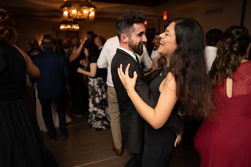 A guest in a black dress dances with Michael while Monica watches nearby.