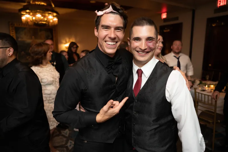Michael poses with a friend at the reception, both smiling as they stand together amid the warmly lit ballroom.