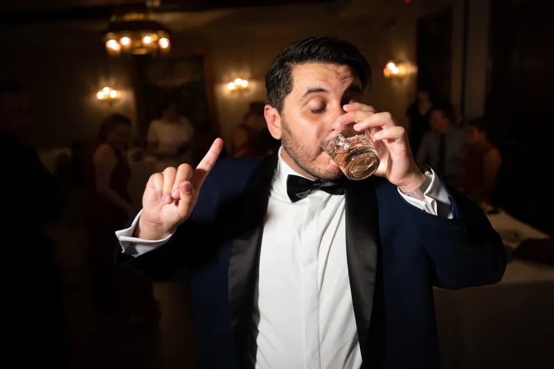 Michael takes a drink during the reception, one hand raised as he enjoys himself in his formal attire.