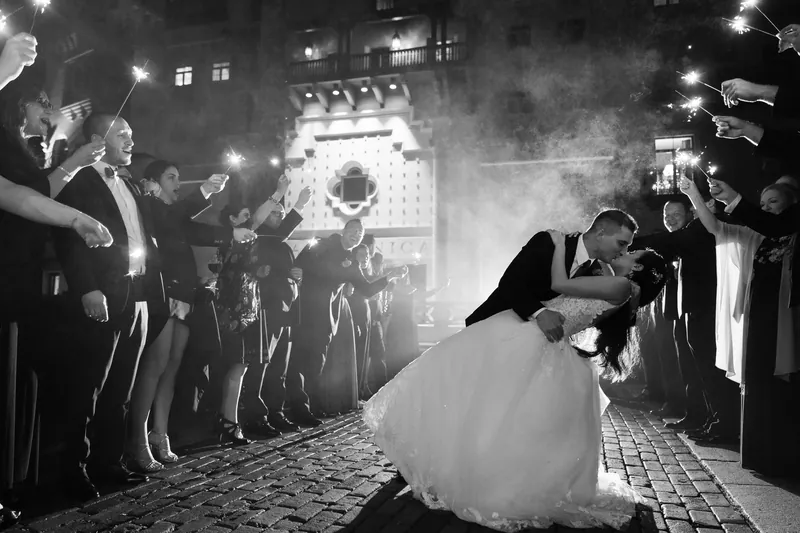 Michael dips Monica in a dramatic kiss beneath the illuminated archway as guests cheer around them.