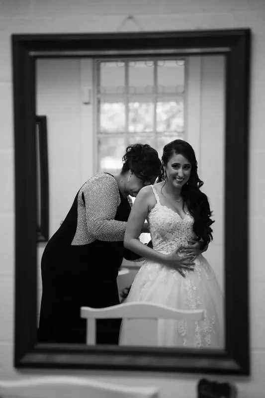 Michael leans in to kiss Monica's cheek as she smiles, captured in a black and white mirror reflection indoors.