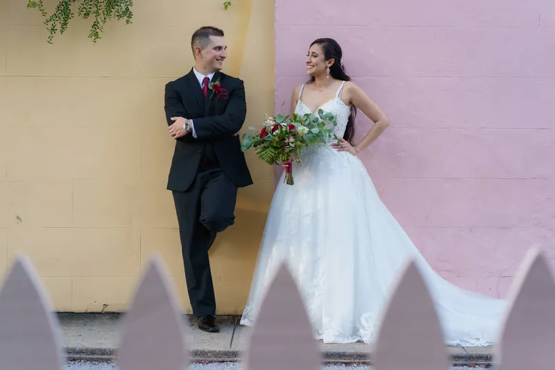 Monica and Michael pose against a two-toned yellow and pink wall, casting long shadows across white steps below.