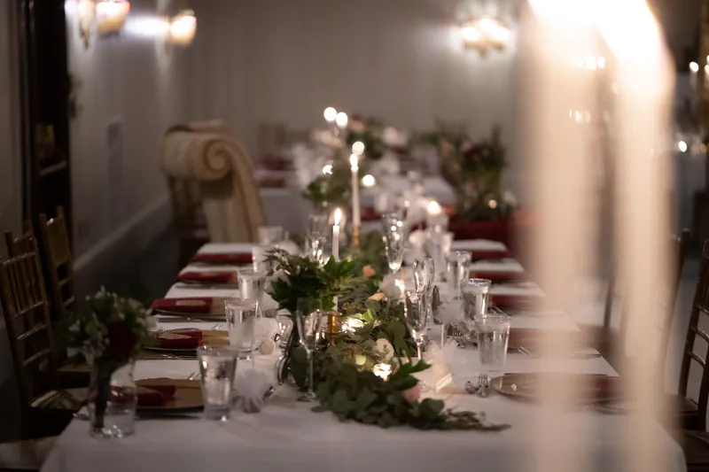 Candlelit reception table with white linens, burgundy napkins, and greenery centerpieces at Casa Monica Resort & Spa.