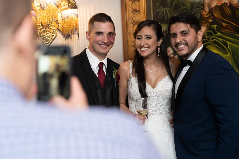Monica poses for a photo with two male guests in the ornate venue.