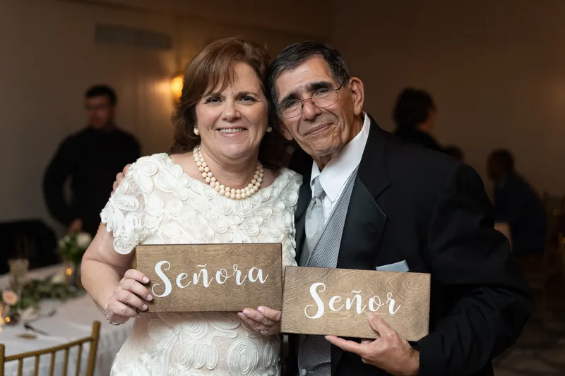 A couple holds wooden signs reading "Senora" and "Senor" at the reception.