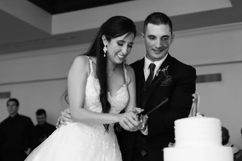 Monica and Michael cut their wedding cake together in black and white.