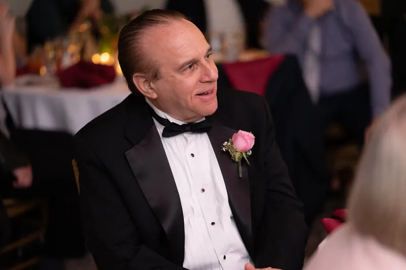 Michael sits in a tuxedo with boutonniere, watching the reception unfold around him at Casa Monica Resort & Spa.
