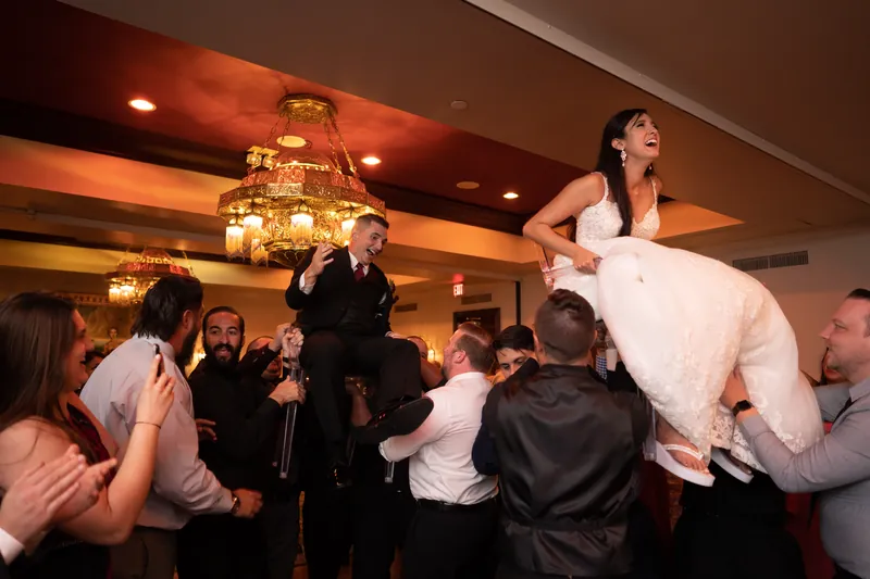 Monica hoisted in the air by wedding guests during a celebratory dance at Casa Monica Resort & Spa.