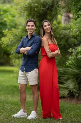 Marco and Natasha stand together in formal attire at Casa Futrell, with greenery framing them outdoors.
