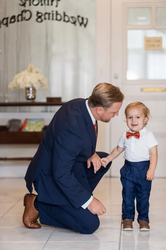 Nathan kneels to tie a small child's shoe inside Lightner Museum's elegant reception space.
