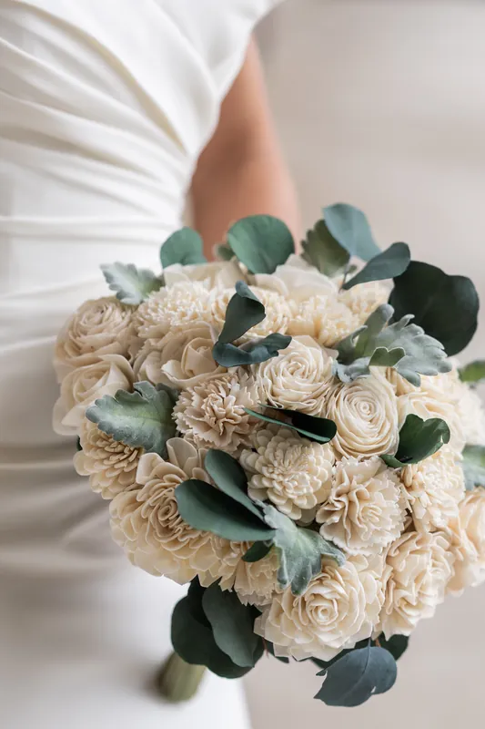 Close-up of cream roses and sage greenery arranged in a cascading bridal bouquet.