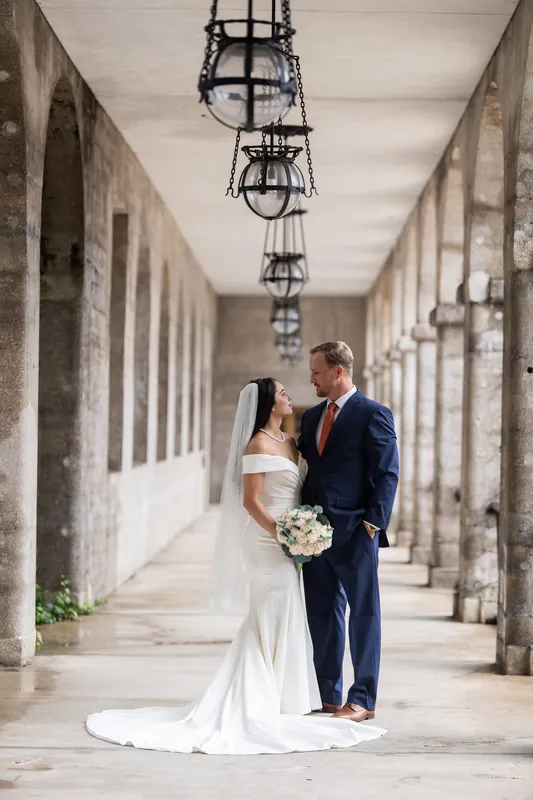 Nathan and Hillary stand together in the Lightner Museum's arched corridor lined with hanging lanterns.