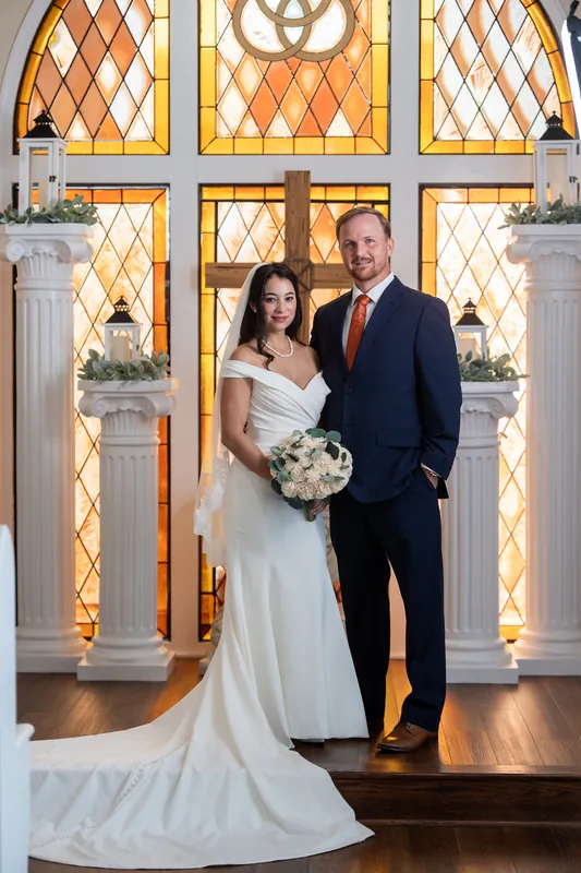 Two people in wedding attire embrace at the museum's columned passageway, foreheads nearly touching.