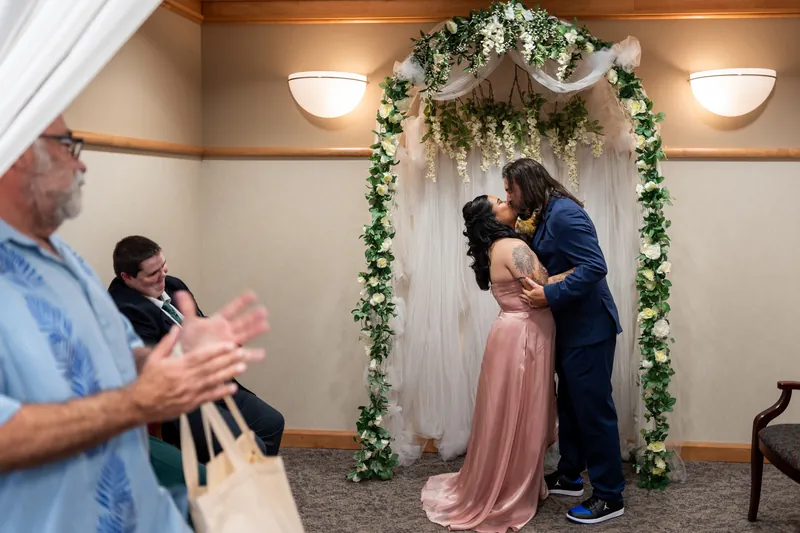 Kiel dips Nikki, who holds her bouquet, while guests applaud beneath the decorated arch.