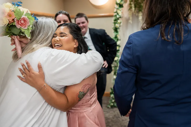 Nikki hugs a guest in a white shirt while Kiel and others stand nearby after the ceremony.