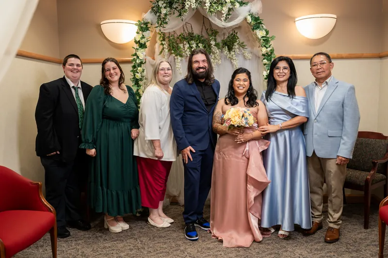 Nikki and Kiel pose with seven family members in front of the greenery arch for a group photo.