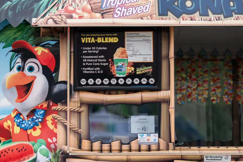 A colorful food stand with cartoon branding displays menu boards and products at Jacksonville Beach, St. Augustine.