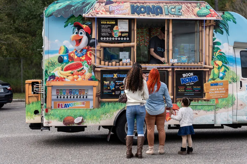 Three children and an adult stand at a colorful shaved ice truck at Jacksonville Beach, St. Augustine.