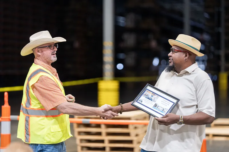 Two event coordinators in cowboy hats exchange a tablet at the rodeo venue in Jacksonville Beach, St. Augustine.