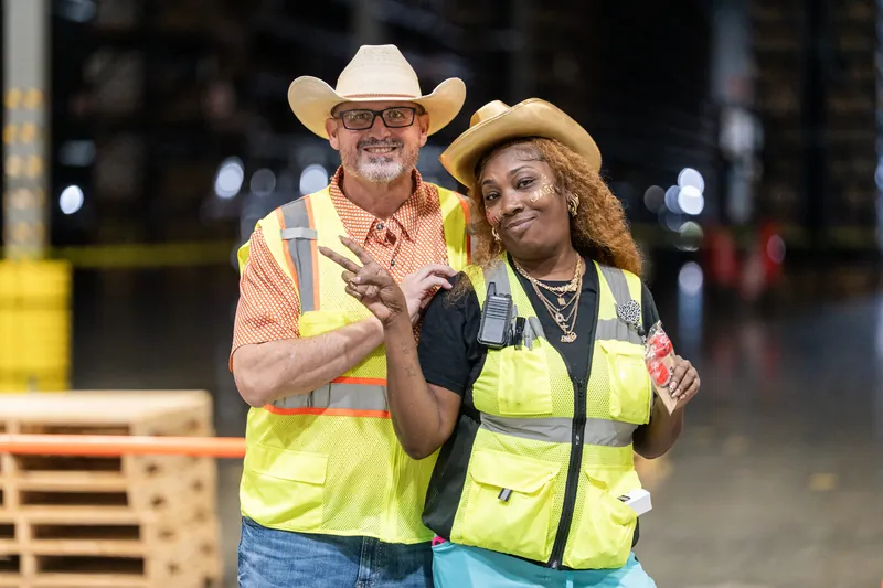 A pair wearing matching neon safety vests and cowboy hats pose together at Jacksonville Beach, St. Augustine.