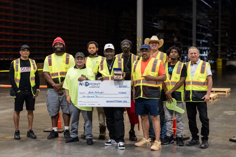 A large group in yellow safety gear holds a check for charity at the pit rodeo in Jacksonville Beach, St. Augustine.