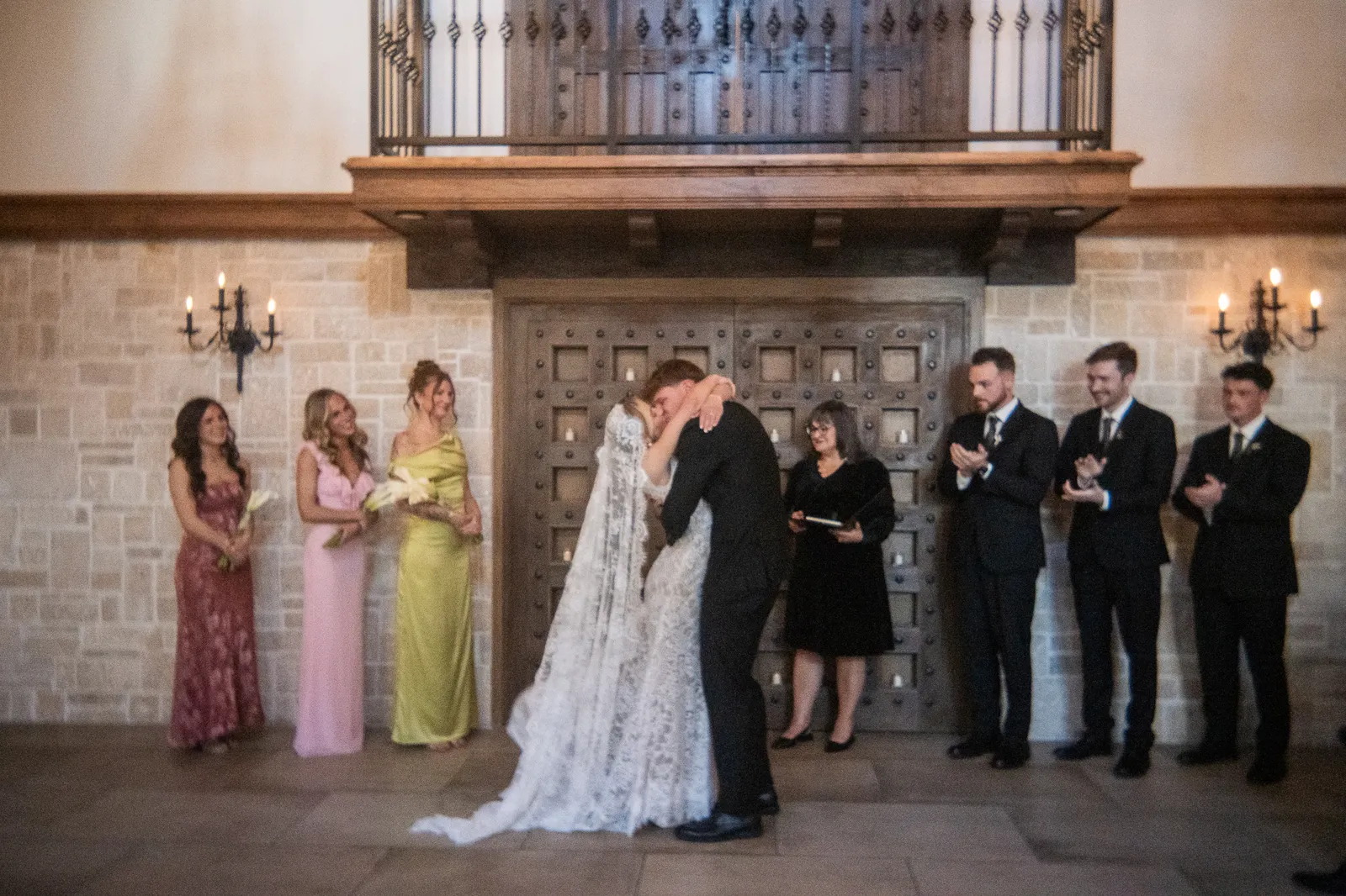 Owen kisses Paige after their ceremony as their wedding party stands witness in the historic venue.