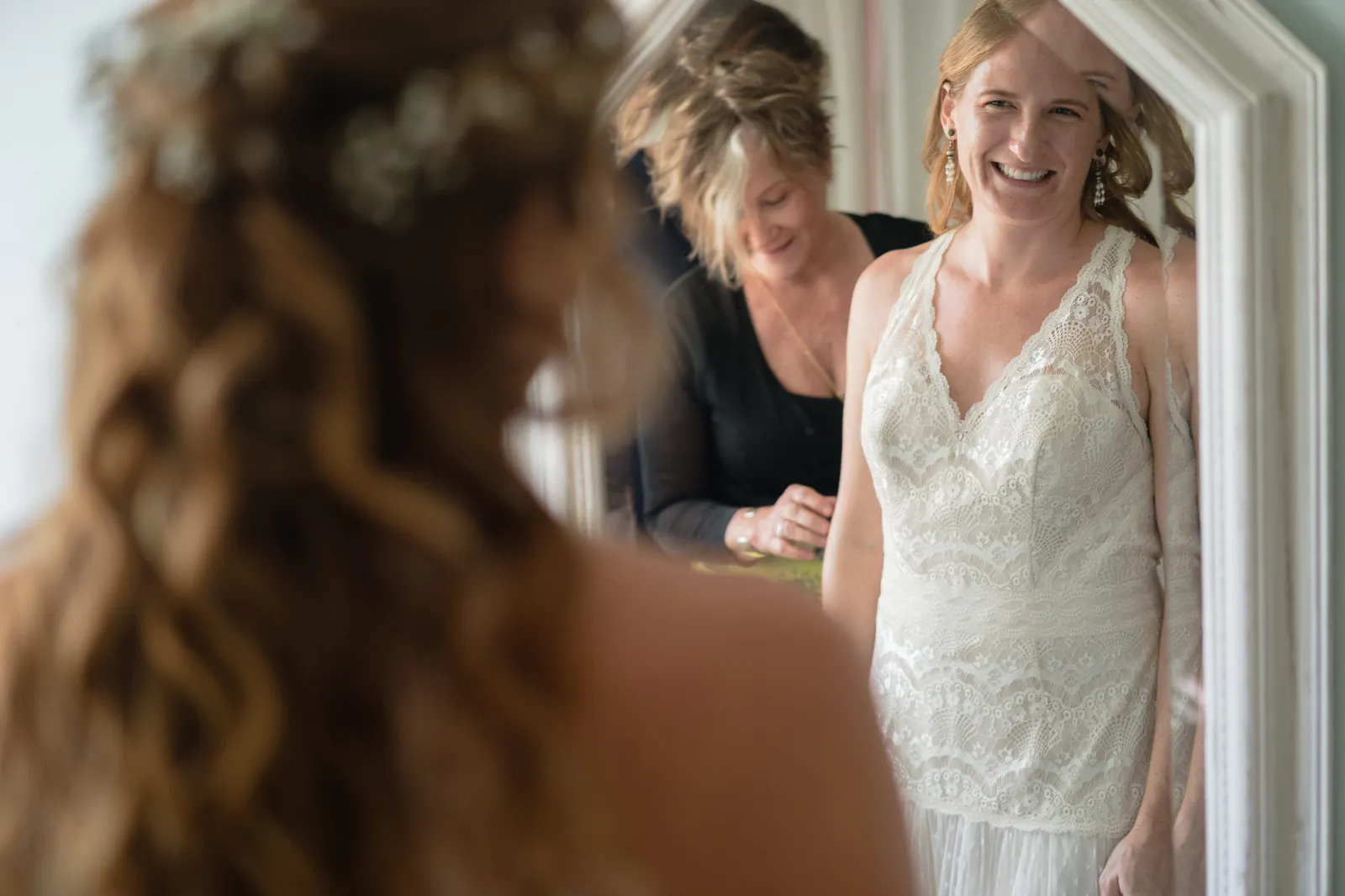 Bride smiling in mirror reflection while getting ready