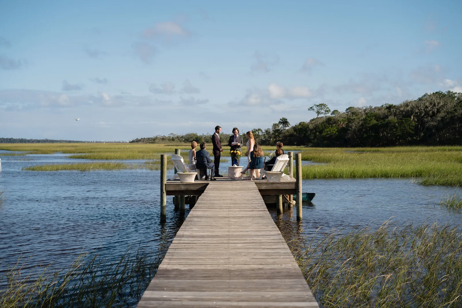 Wide view of intimate dock ceremony with family in Adirondack chairs