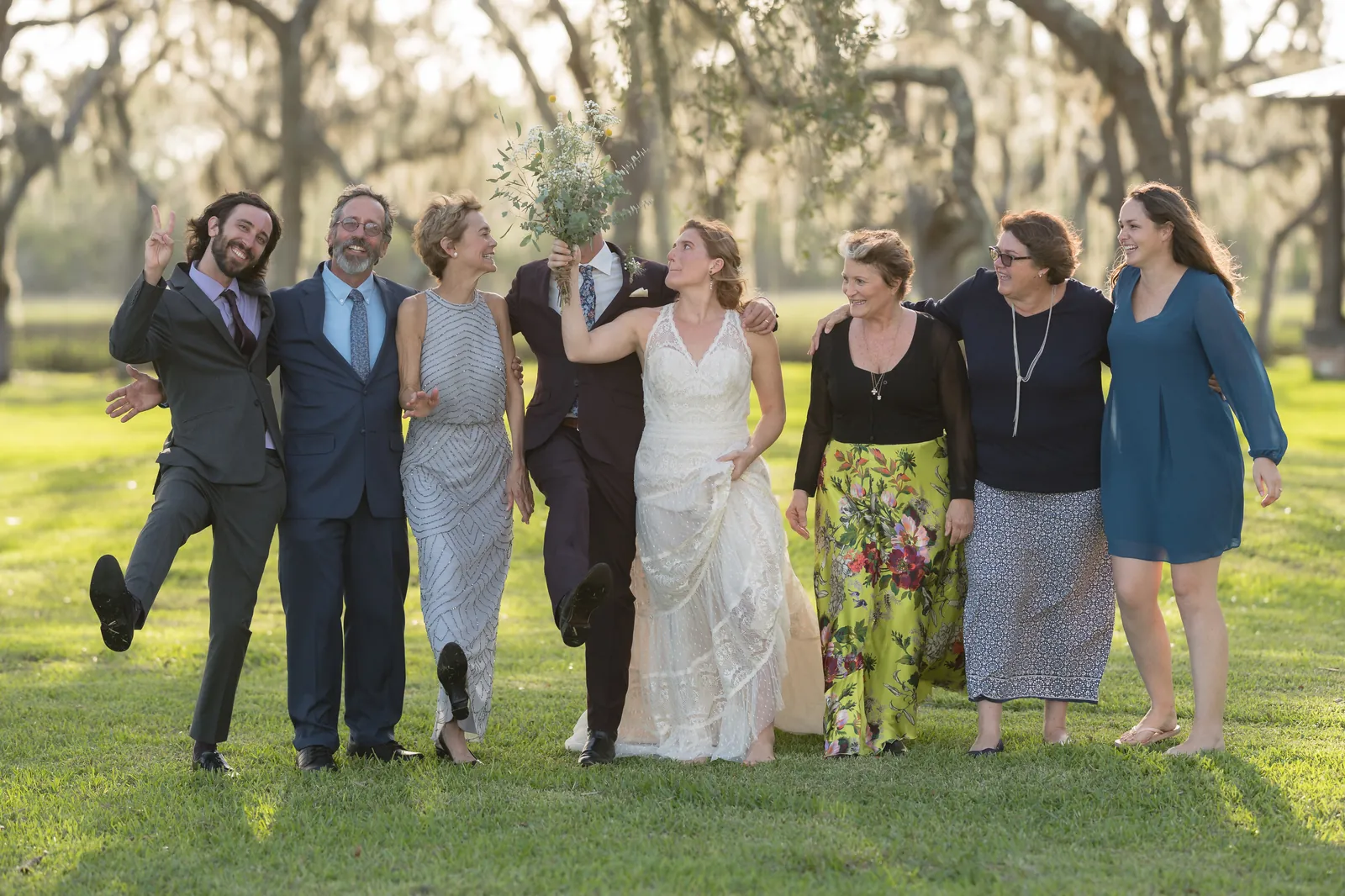 Fun family group photo with everyone being playful under oaks
