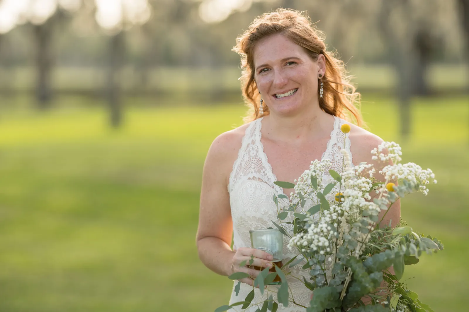 Full-length bridal portrait with wildflower bouquet on green lawn