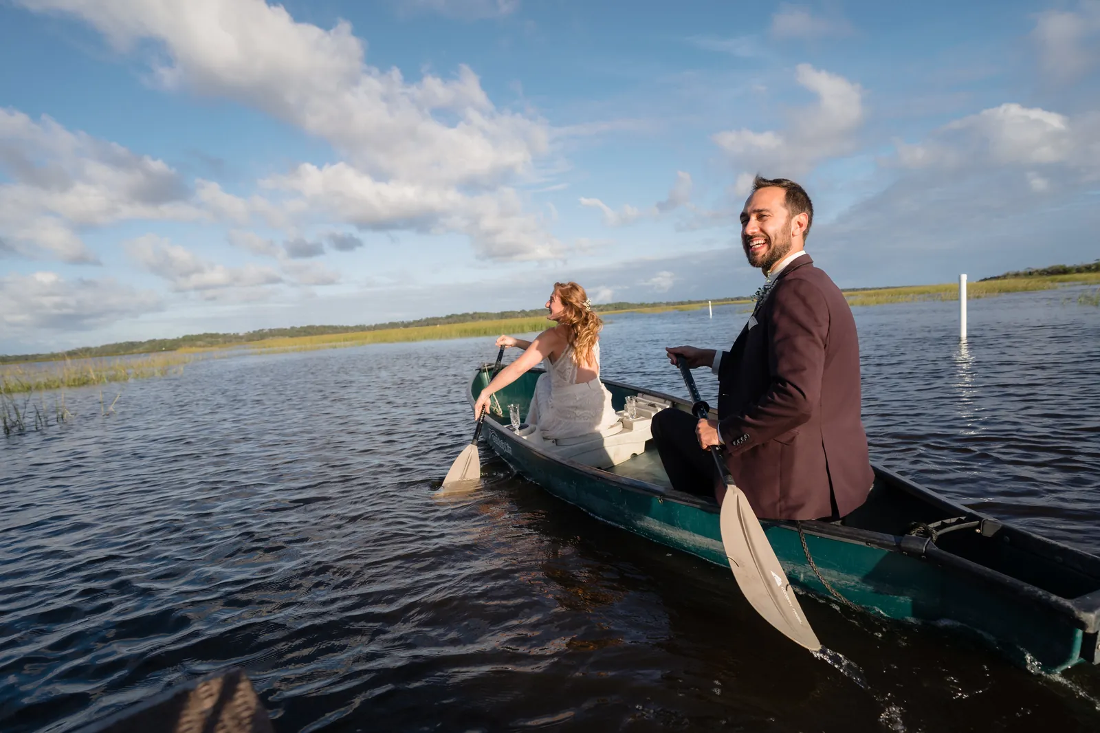 Couple paddling canoe through the marsh from behind
