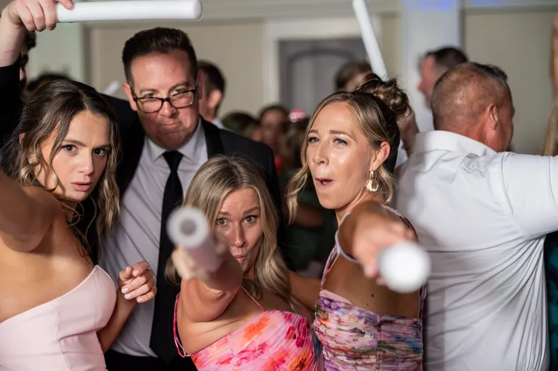 Guests clap and cheer as the couple dances surrounded by friends holding glow sticks at Crosswater Hall.