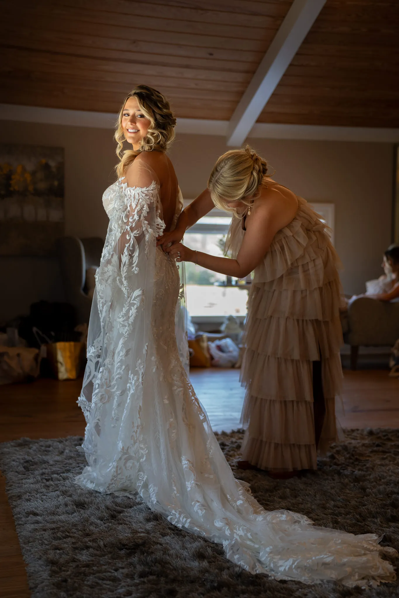 Bride Riley getting ready with bridesmaid zipping dress at Tringali Barn