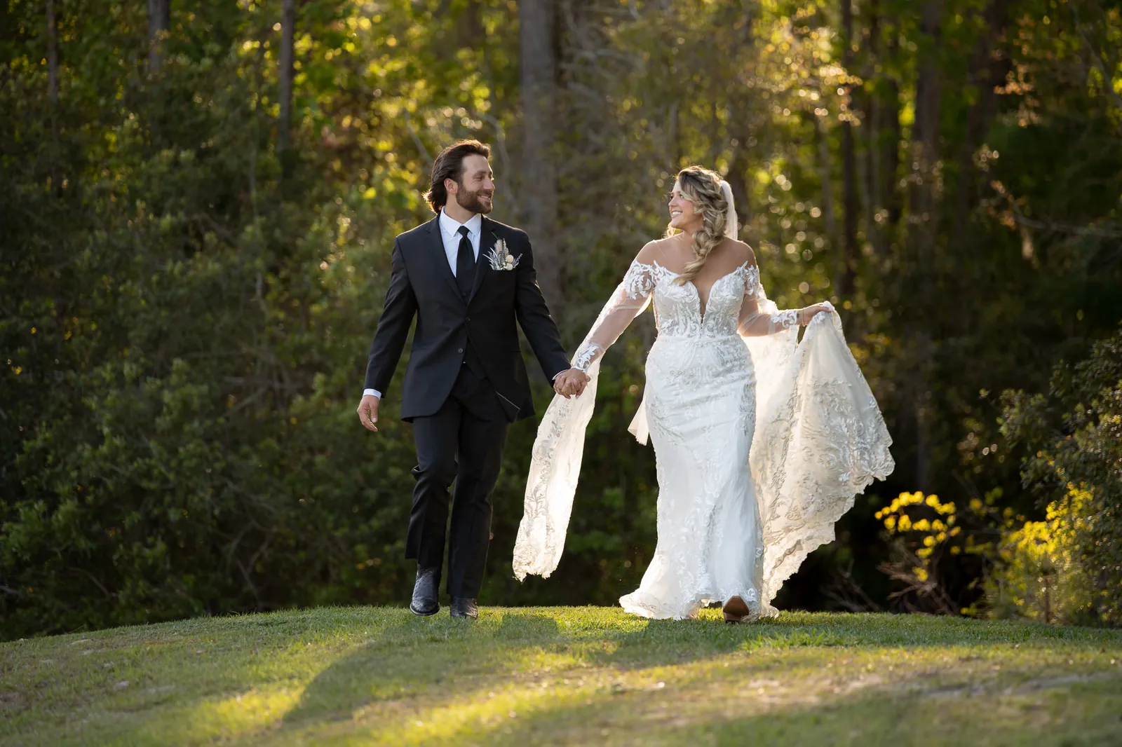 Riley and Robert walking hand in hand at golden hour at Tringali Barn