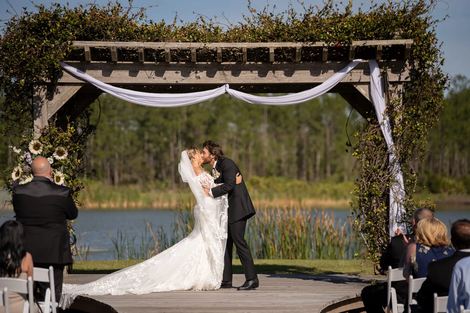 First kiss under pergola with lake backdrop at Tringali Barn wedding