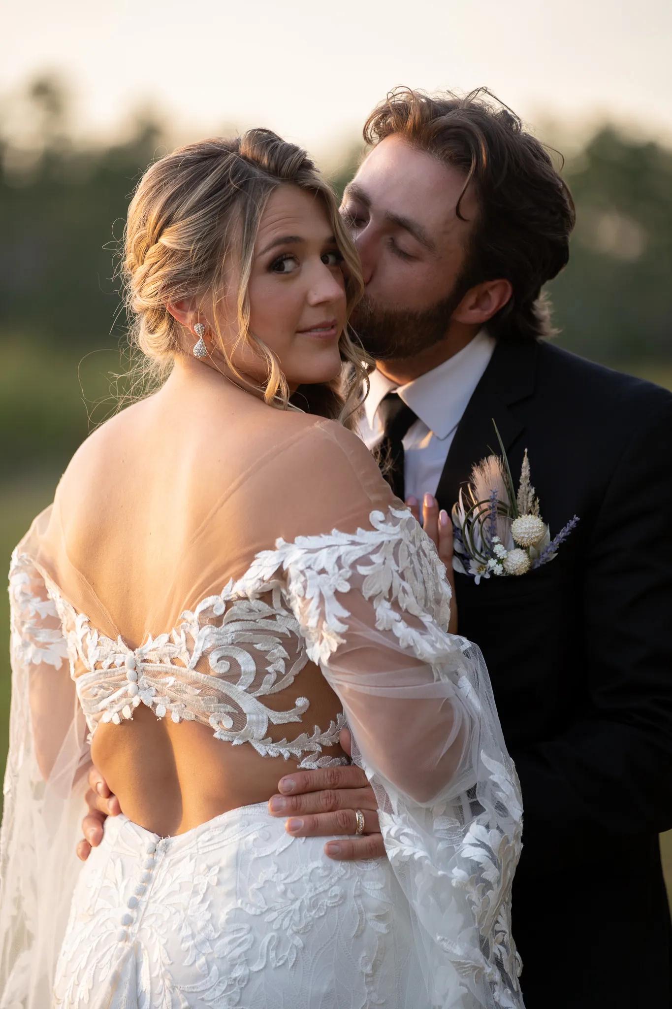 Groom Robert kissing bride Riley on cheek at golden hour at Tringali Barn