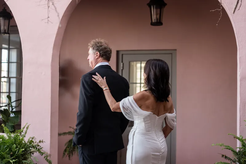 Bill and Rose Ann walk together under The White Room's pink arched entryway before their ceremony.