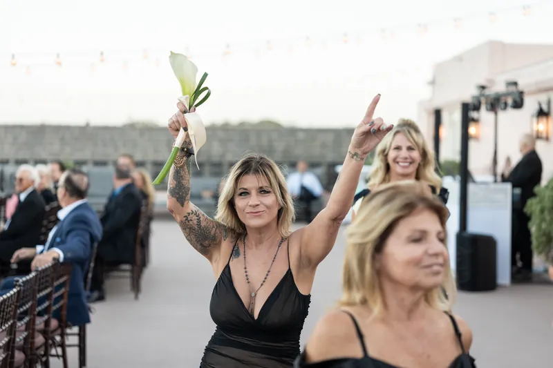 Guest catches bouquet toss at The White Room reception with arms raised and genuine smile.