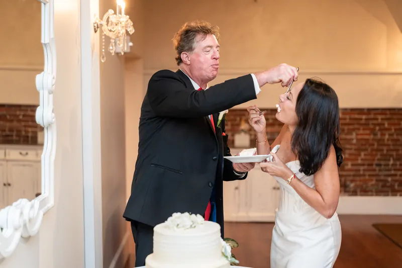 Bill feeds Rose Ann a piece of cake during their first cake cut at The White Room reception.
