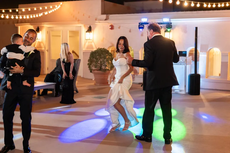Rose Ann dances with a guest while Bill watches at The White Room's lit dance floor during their reception.
