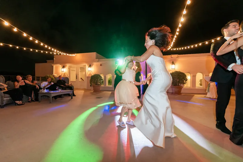 Rose Ann and Bill dance together on the colorful lit dance floor at The White Room under string lights.