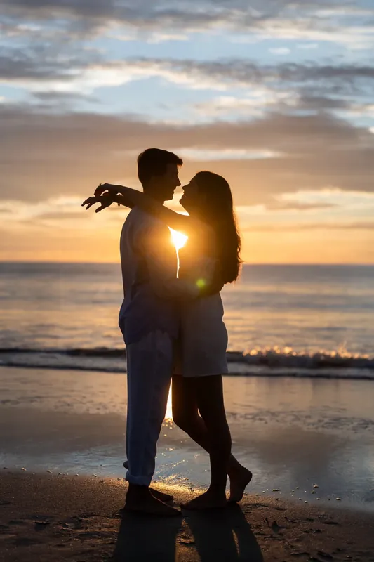 Silhouetted against the golden sunset, Pasha lifts Sally as they kiss at the water's edge on the beach.